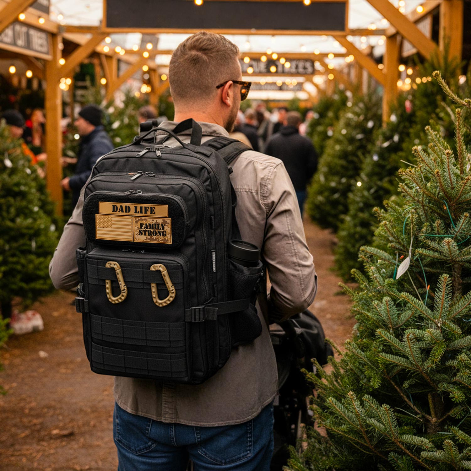 Man with a black backpack diaper bag for men labeled 'dad Life' in a Christmas tree lot.