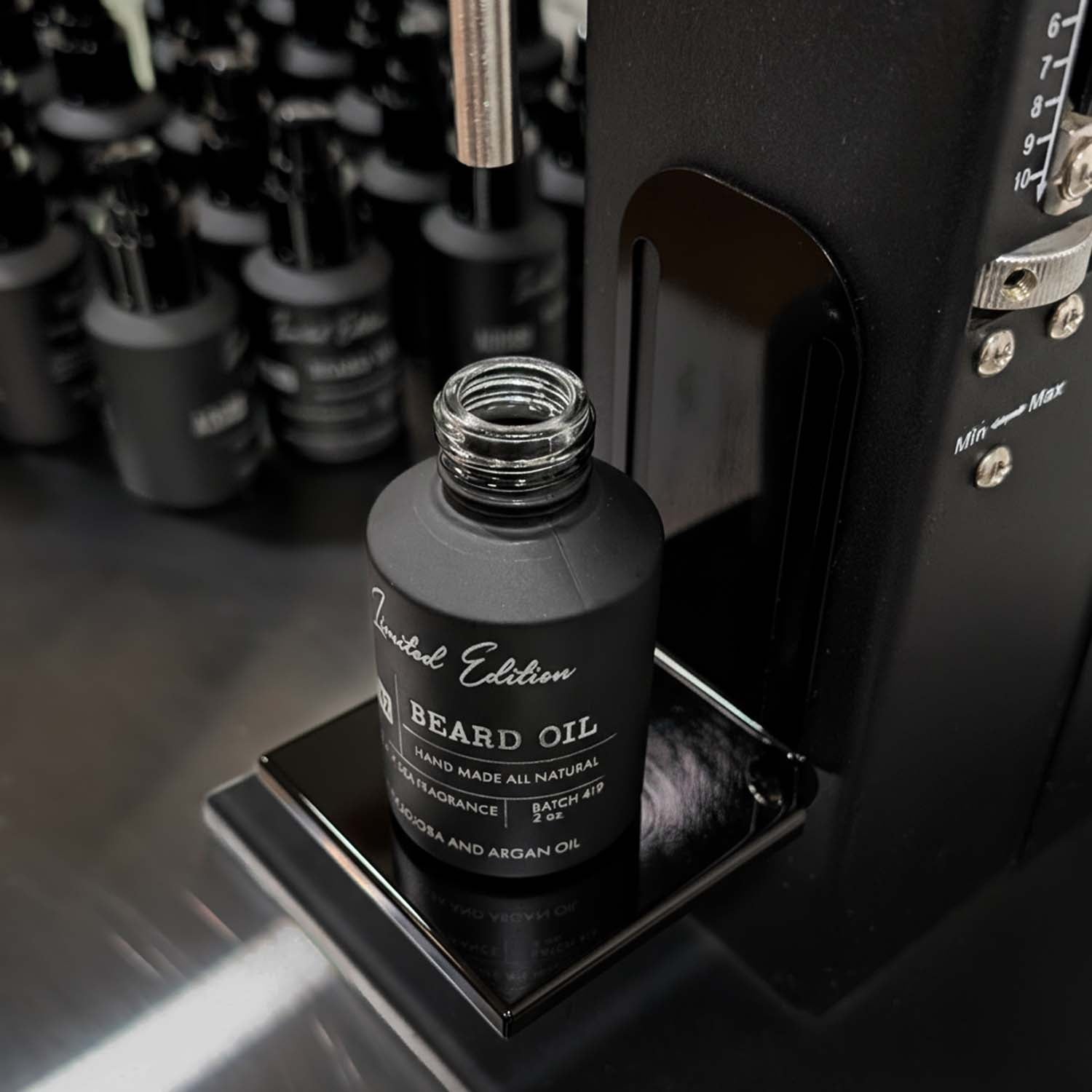 Black beard oil bottle labeled 'Limited Edition' on a reflective surface with blurred background