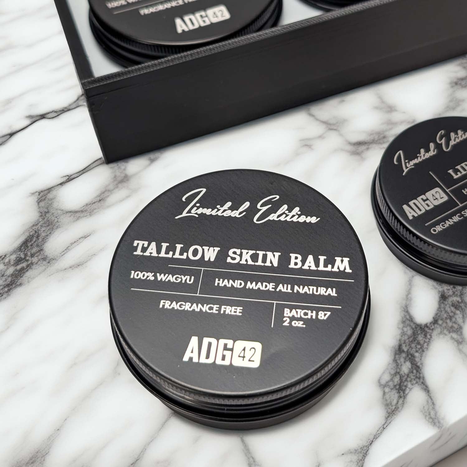 Tallow skin balm containers with 'ADG42' branding on a marble surface