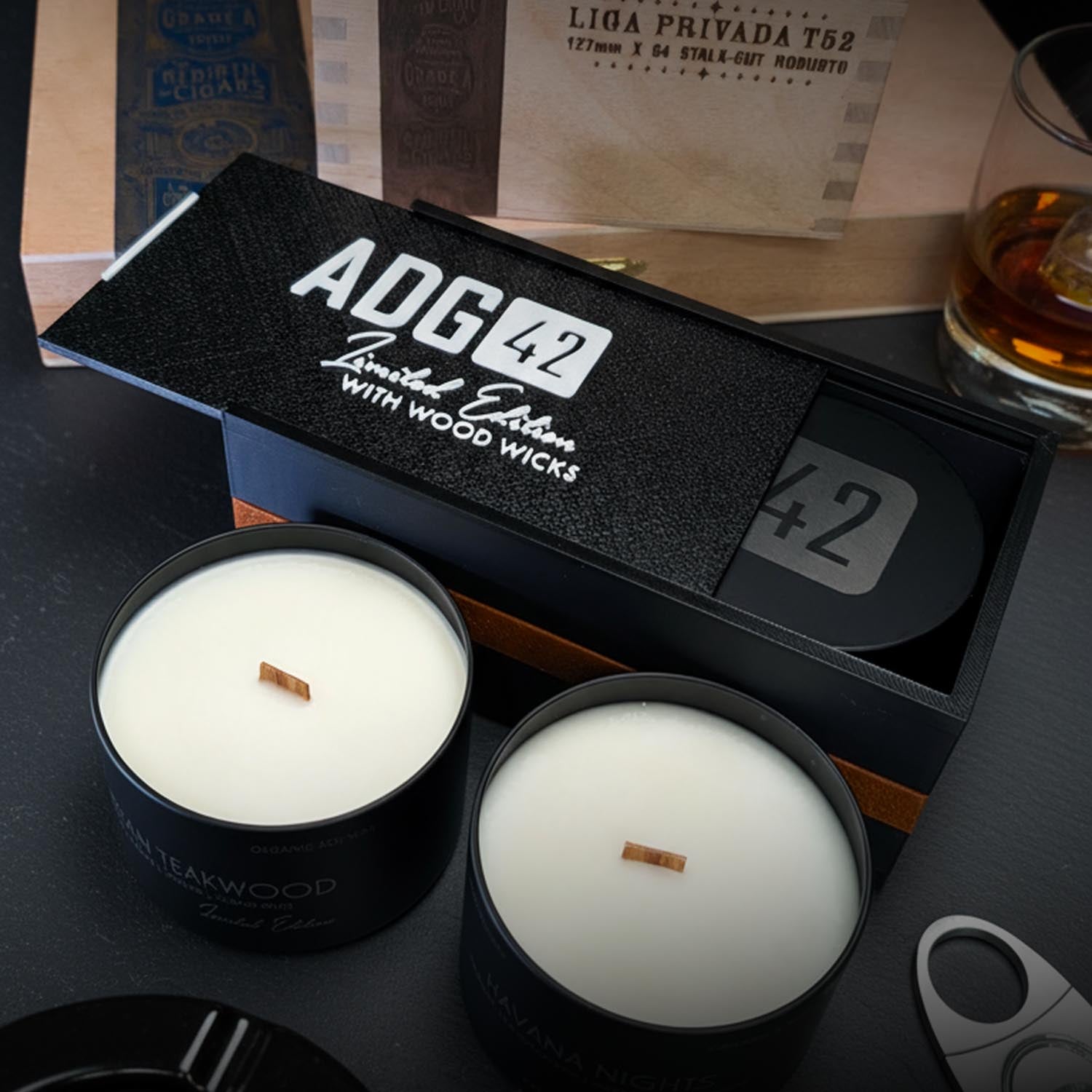 Two candles for men in black containers with a 'ADG 42' branded box on a dark surface.