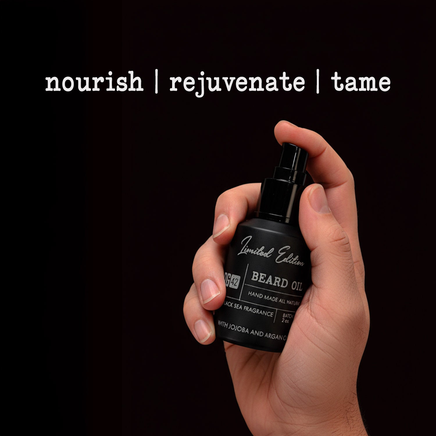 Hand holding a black beard oil bottle with text 'nourish | rejuvenate | tame' on a black background